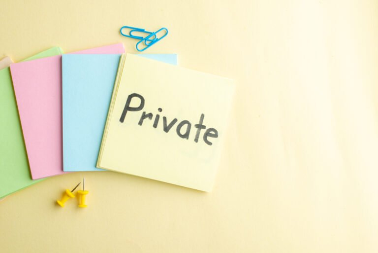 Colorful sticky notes with the word ‘Private’ written on the top note, surrounded by push pins and paperclips on a light background
