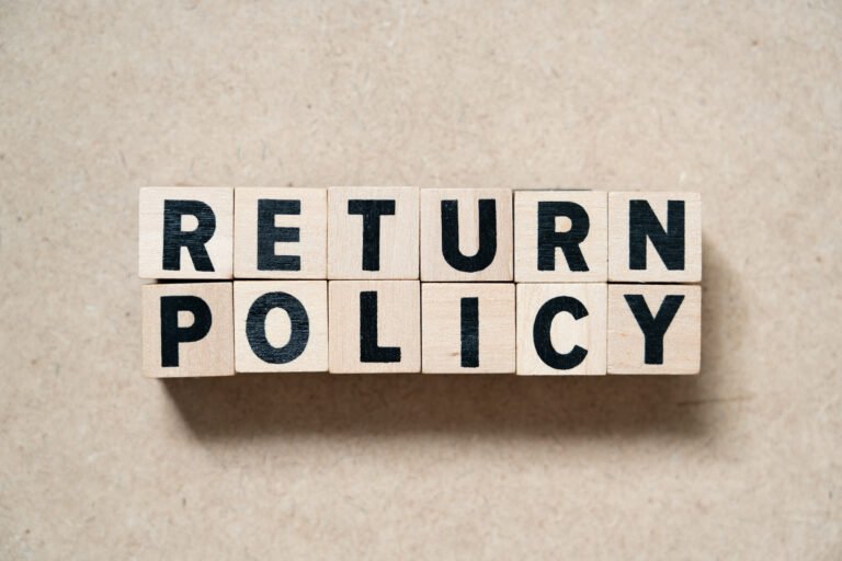 Wooden blocks spelling out the words ‘Return Policy’ on a neutral background.